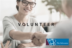 [ai] A woman wearing glasses smiling and shaking hands with another person across a table, with a logo of 'The Advocates for Human Rights' in the bottom corner. The word 'VOLUNTEER' is overlaid on the image.